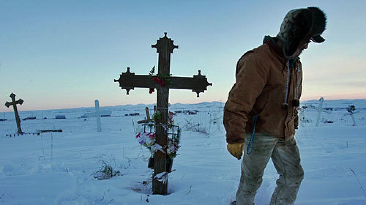 PAYING RESPECTS: Thomas Cheemuk visits the grave of his brother John, who killed himself in 1999, in a cemetery overlooking the Alaska village of St. Michael in February.