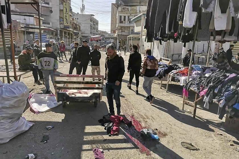 Residents at the site of a deadly bomb attack in Baghdad's bustling commercial area on Thursday.