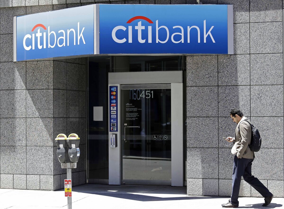 A man walks past a branch of Citibank in San Francisco in 2014. The bank has agreed to refund about $700 million for illegal credit card practices.