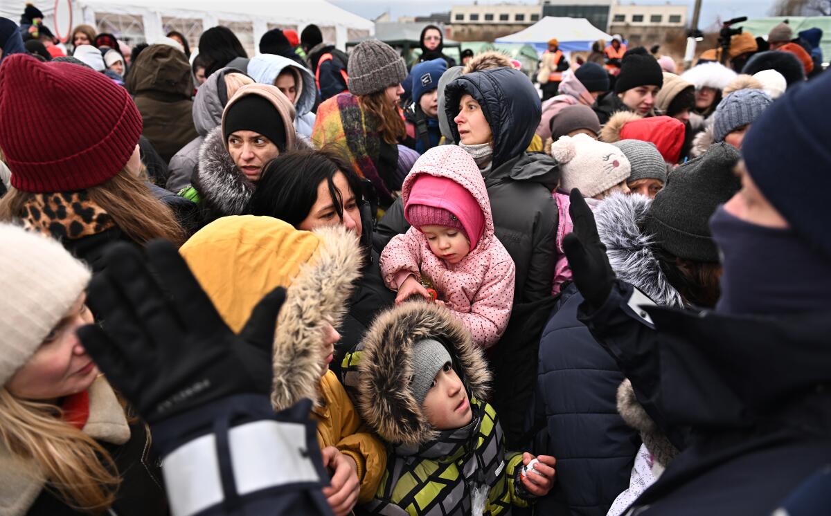 Anxious Ukrainian refugees start push toward a bus.