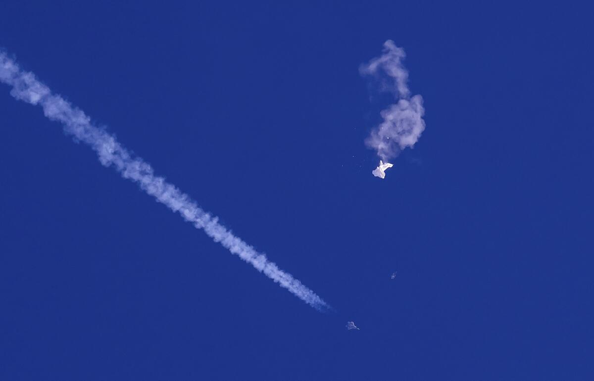 White smoke and a white blob in a blue sky.