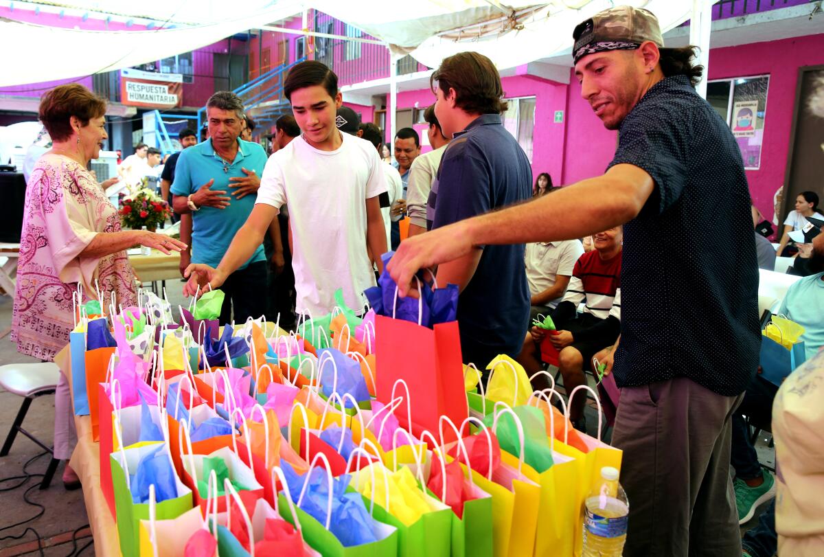 A man grabs a gift bag among many colorful ones near other men standing nearby