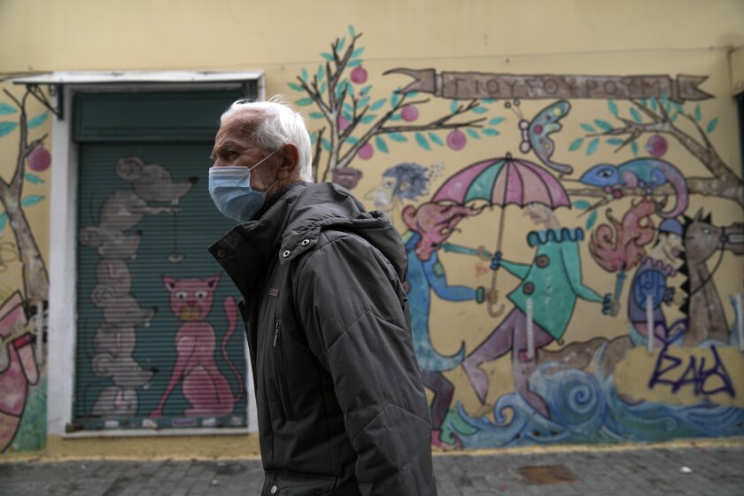 Un hombre con mascarilla para protegerse del coronavirus camina en Atenas, Grecia, el lunes 29 de noviembre de 2021. (AP Foto/Thanassis Stavrakis)