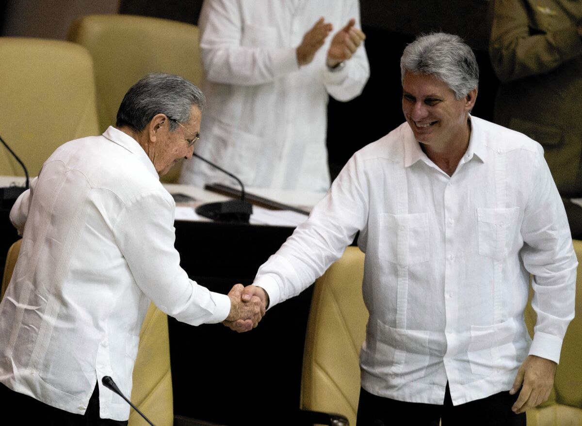 Miguel Diaz-Canel, right, shakes hands with Cuban President Raul Castro. Castro's appointment of Diaz-Canel as first vice president in 2013 set him up as heir apparent of Cuba.
