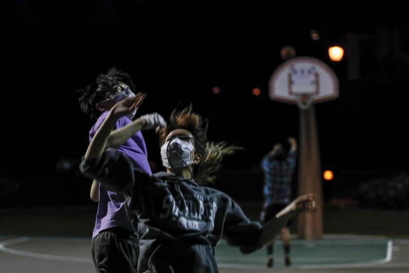 AZUSA, CA, MONDAY, MARCH 30, 2020 - Young friends play a spirited game of one-on-one basketball despite posted warnings that the Sierra Madre Park grounds are closed due to the Coronavirus pandemic. They would not give their names, but one of their friends said they were concerned that people would think they were infected with the virus. Yet she expressed no concern that the friends, who don't live in the same house, are not practicing social distancing. (Robert Gauthier/Los Angeles Times)