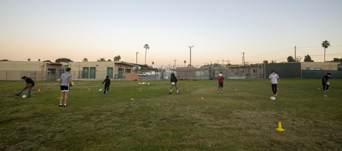 Orange County Soccer Club's Rob Kiernan, second from the left, gives instructions to students at the Save Our Youth campus.