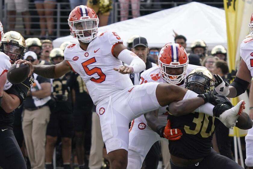 Clemson's DJ Uiagalelei looks to pass as Wake Forest defensive lineman Jasheen Davis (30) grabs his leg Sept. 24, 2022.