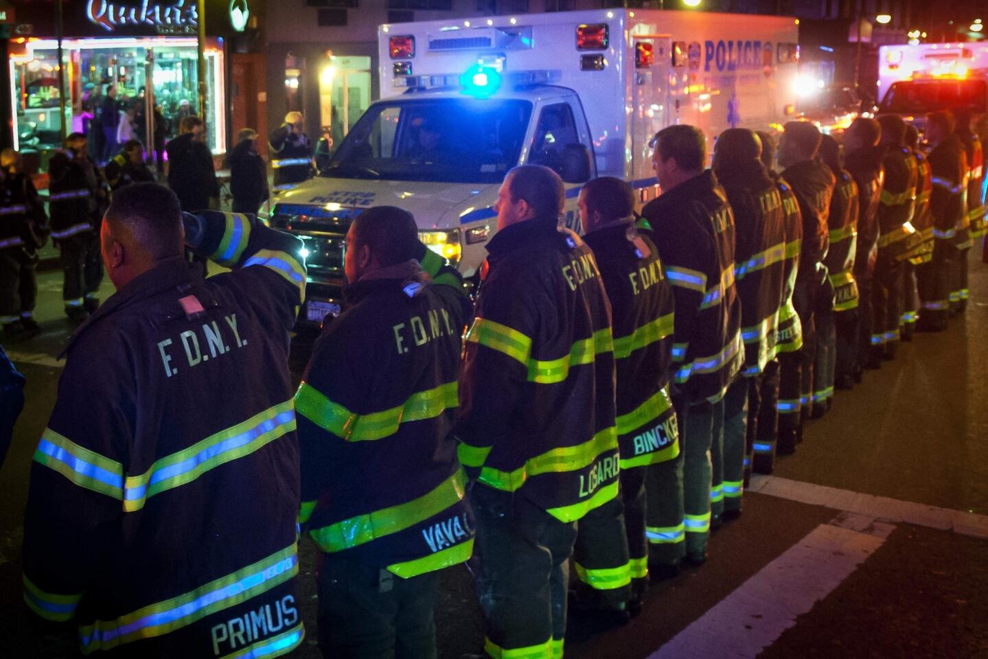 An ambulance carrying one of the two New York Police officers who were shot dead passes by a New York Fire Department honor guard along Broadway in the Brooklyn borough of New York