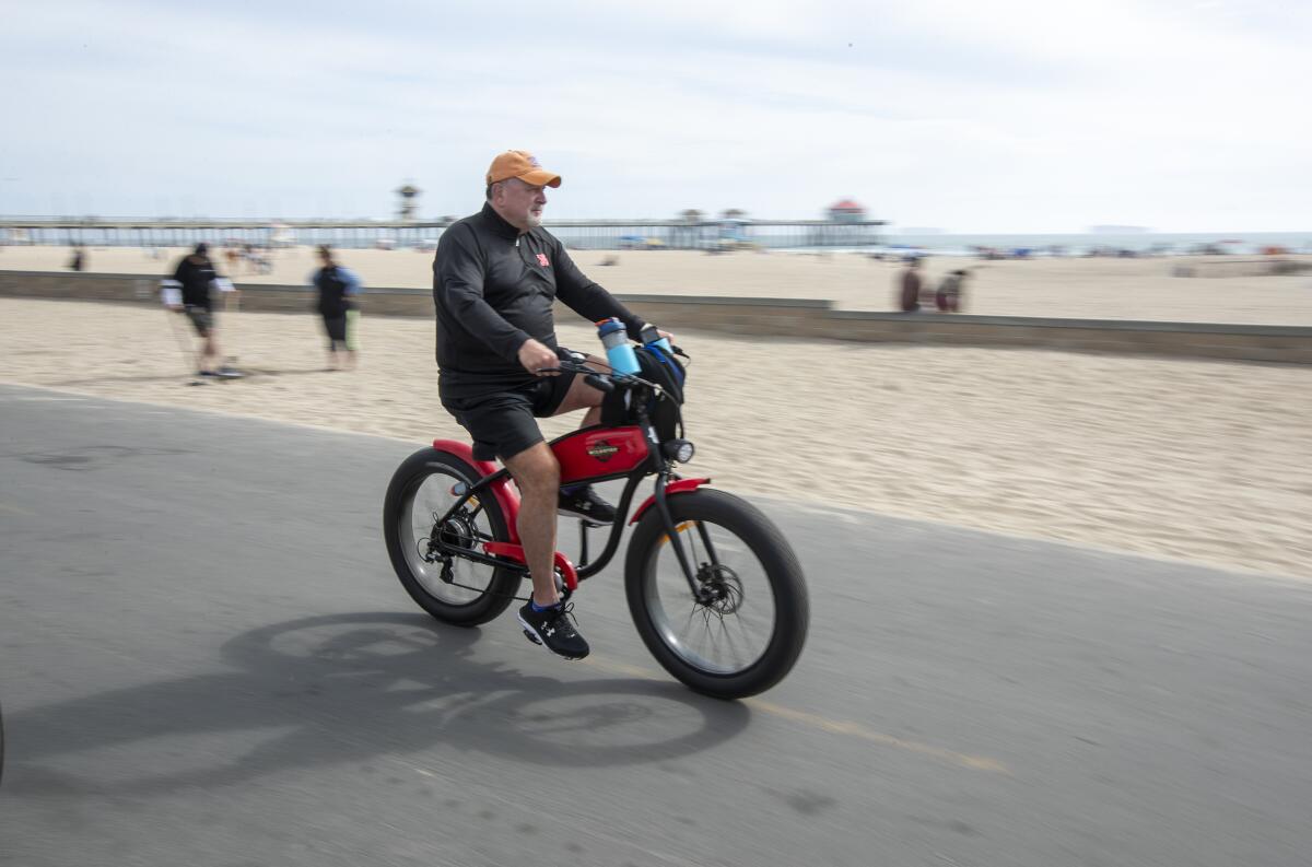 A man rides an e-bike on the bike path in Huntington Beach.