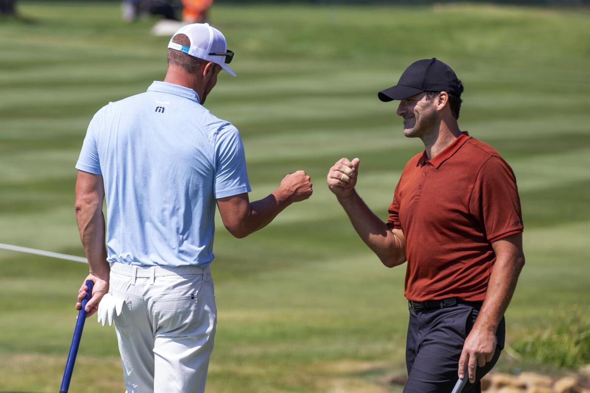 Tony Romo, right, fist bumps Mark Mulder after sinking the winning putt on the 18th hole during the final round of the American Century Celebrity Championship golf tournament at Edgewood Tahoe Golf Course in Stateline, Nev., Sunday, July 10, 2022. (AP Photo/Tom R. Smedes)