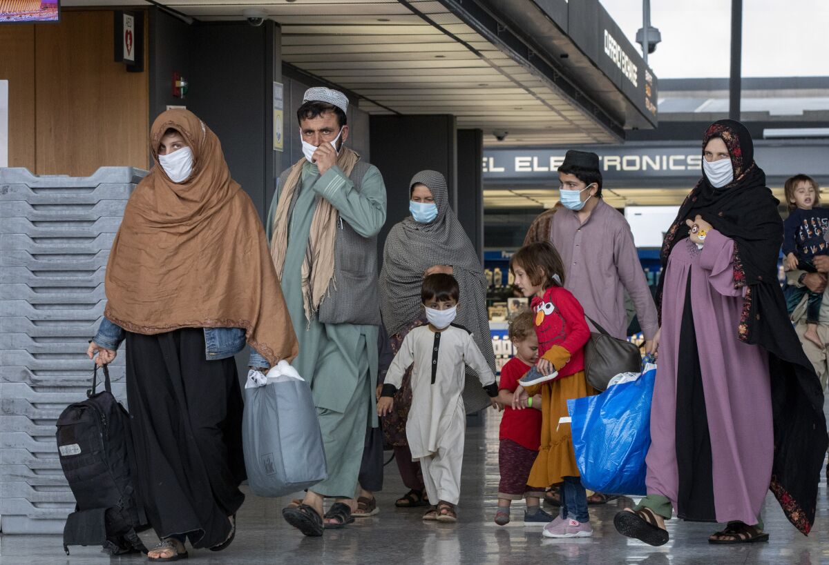 FILE - Families evacuated from Kabul, Afghanistan, walk through the terminal to board a bus