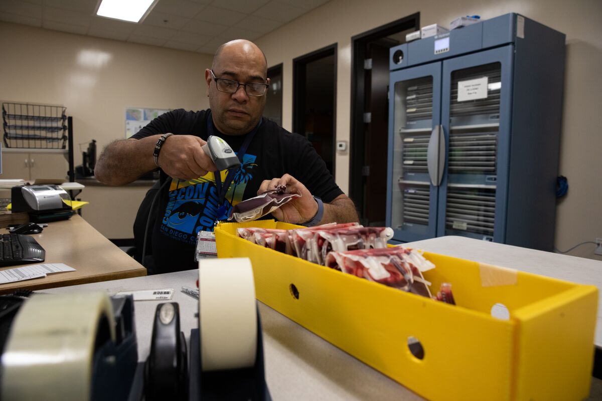 Hospital Services Representative Damaso Asencio scans bags of donated blood that will be sent to Hoag Newport Beach Hospital