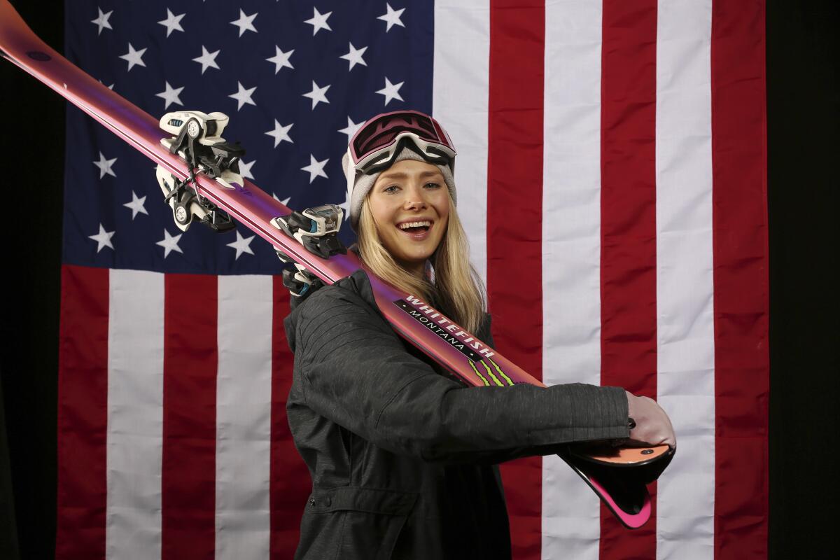 Maggie Voisin poses with skis in front of an American flag.