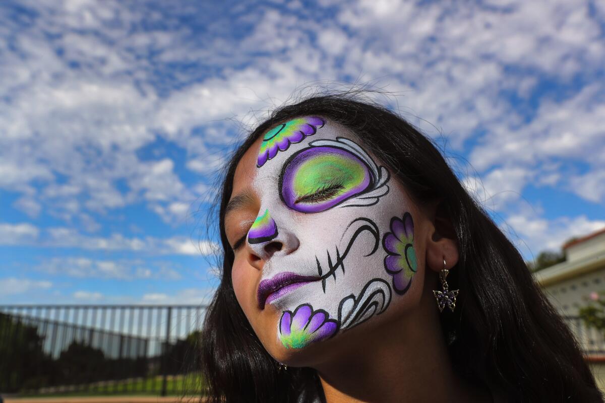 A girl with floral skull features painted over half her face