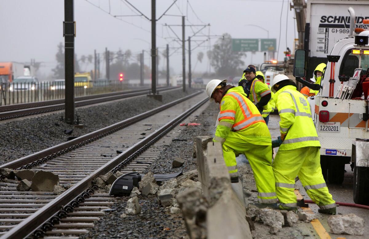 Caltrans workers repair a portion of a roadside barrier after big rig crash on the eastbound 210 Freeway at Sierra Madre Boulevard early Thursday morning, backing up auto traffic and temporarily suspending Metro rail service.