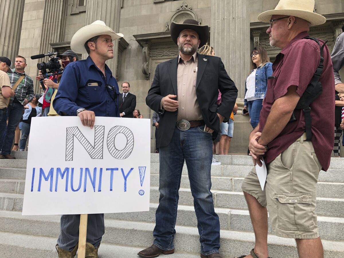 Protesters including Ammon Bundy stand on the steps of the Idaho Capitol.