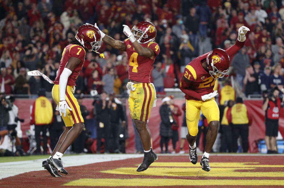USC defensive back Calen Bullock reacts with defensive backs Max Williams and Latrell McCutchin after intercepting a pass.