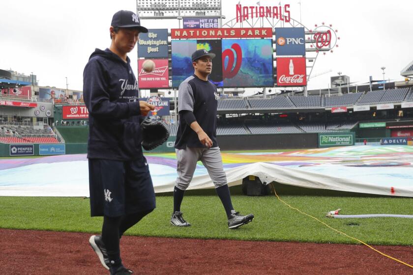 New York Yankees starting pitcher Masahiro Tanaka, center, and his translator, Shingo Horie, left, walk off the field at Nationals Park after it was announced that both of today's interleague baseball games against the Washington Nationals have been postponed due to inclement weather, Wednesday, May 16, 2018, in Washington. Both game have been rescheduled for June 18, 2018. (AP Photo/Pablo Martinez Monsivais)