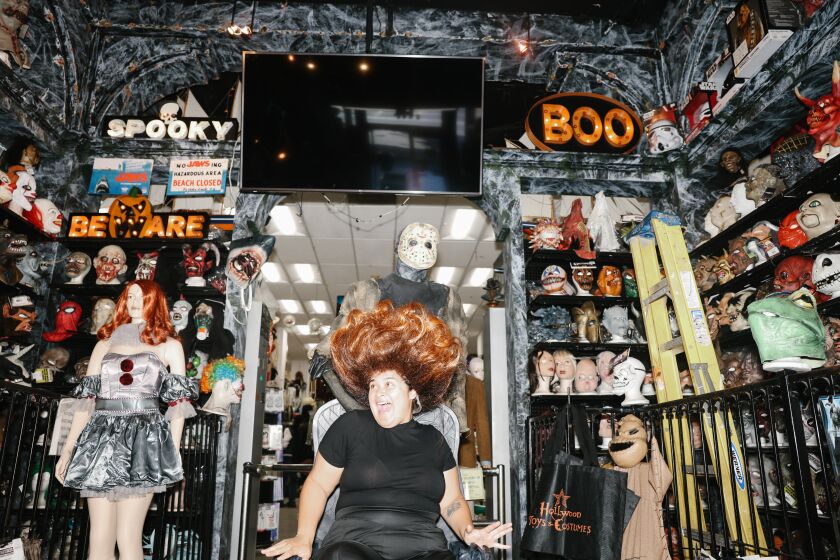 Los Angeles, CA - October 05: Employee Danelly Alexis tries on a wig at Hollywood Toys & Costumes on Wednesday, Oct. 5, 2022 in Los Angeles, CA. The store is considered one of the best for halloween in the city. (Dania Maxwell / Los Angeles Times)