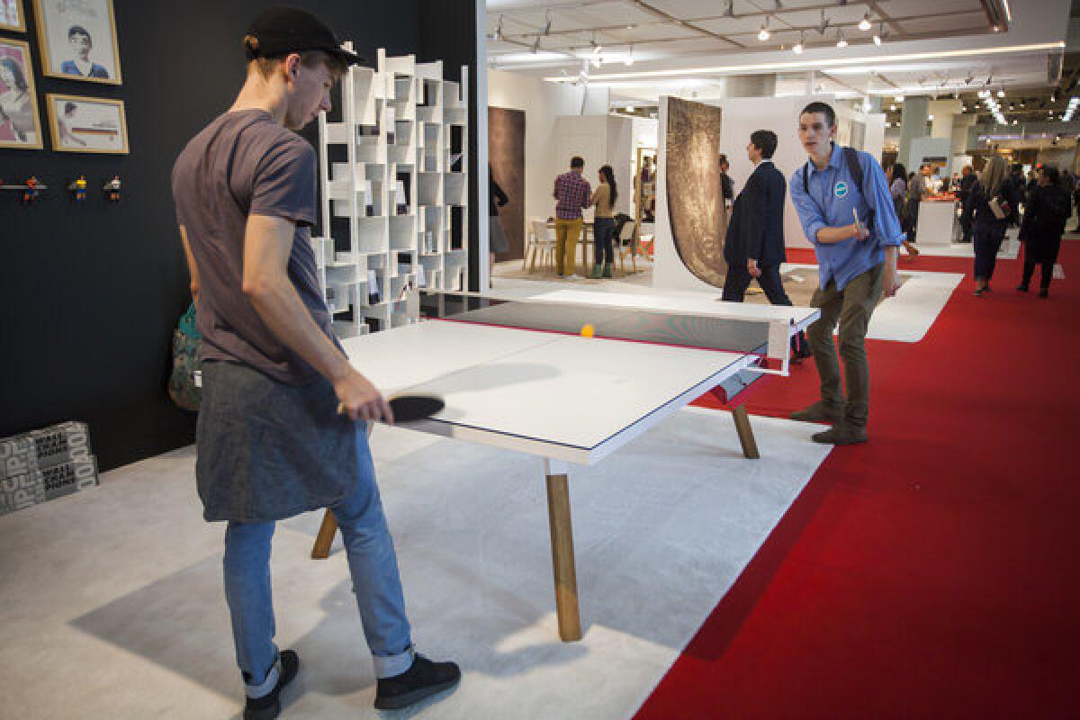 Students try out the You & Me table designed by Antoni Palleja Office during the International Contemporary Furniture Fair, the most important U.S. show for modern home design, held at Javits Center in New York.