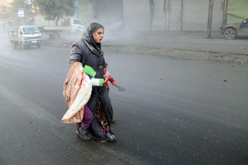 A wounded Syrian woman walks with her children after airstrikes on a rebel area of the war-torn northern city of Aleppo.