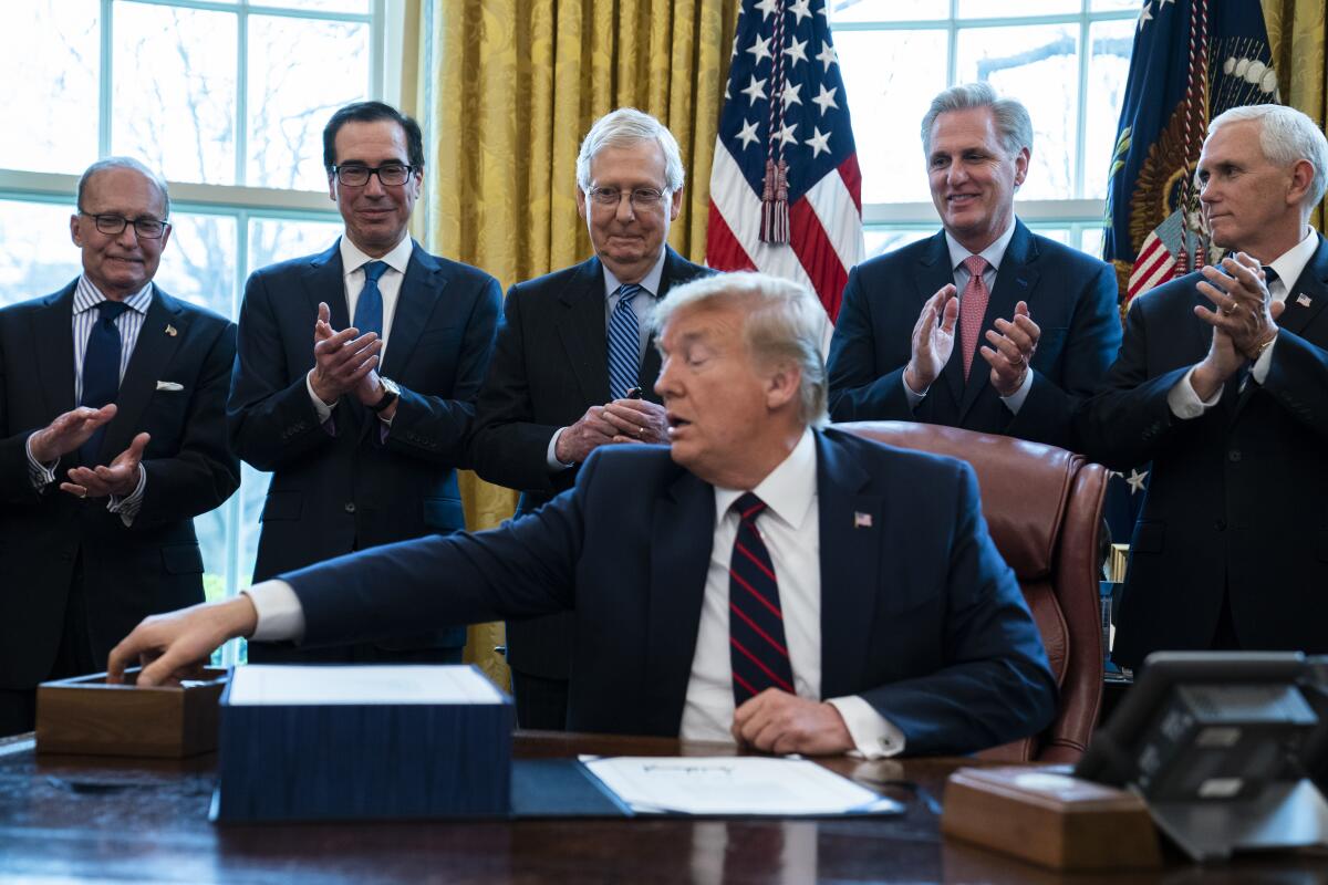 Surrounded by White House aides and GOP congressional leaders, President Trump signs the $2-trillion bailout bill Friday. From left, White House chief economic advisor Larry Kudlow, Treasury Secretary Steven T. Mnuchin, Senate Majority Leader Mitch McConnell (R-Ky.), House Minority Leader Kevin McCarthy (R-Bakersfield) and Vice President Mike Pence. 