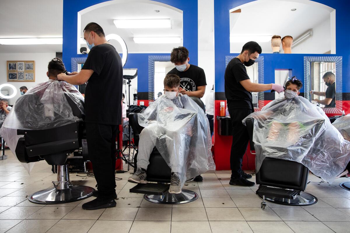 Three boys get their hair cut by barbers during the Back-To-School Haircut Drive.