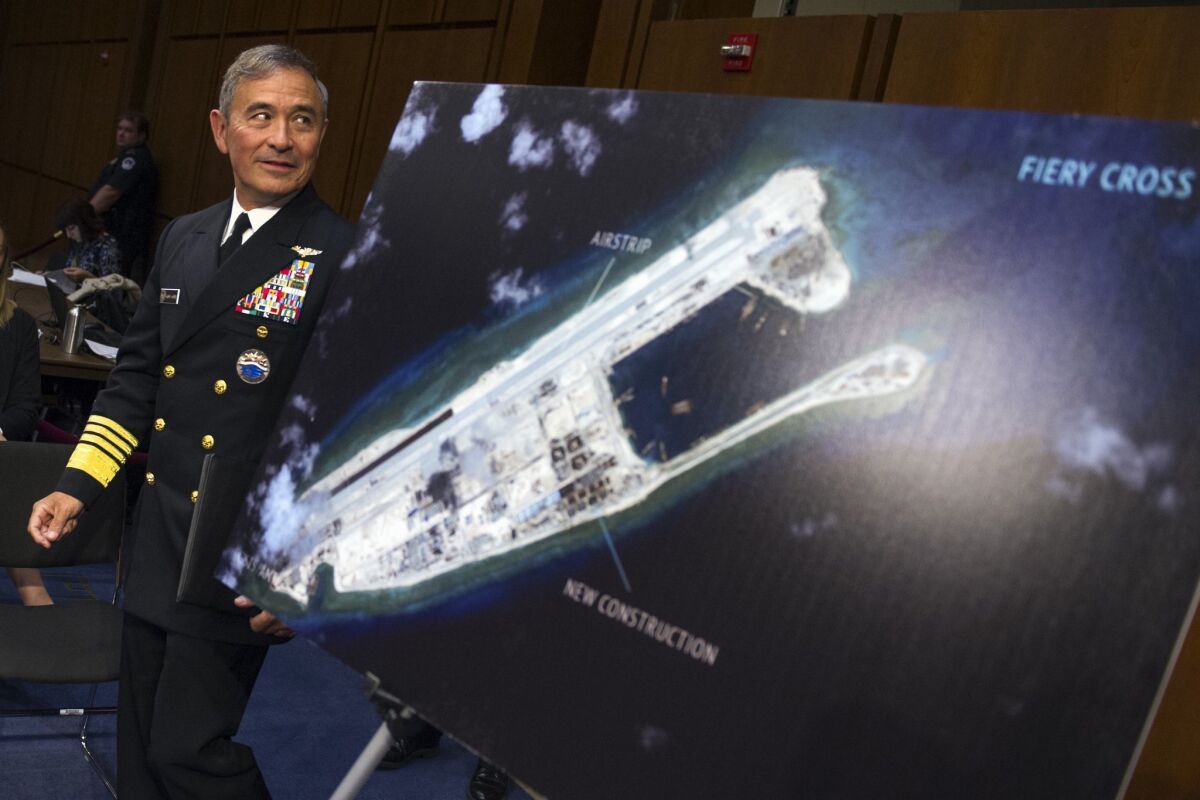During a Sept. 17 congressional hearing, Navy Adm. Harry B. Harris Jr. walks past a photograph showing an island that China is building on the Fiery Cross Reef in the South China Sea.