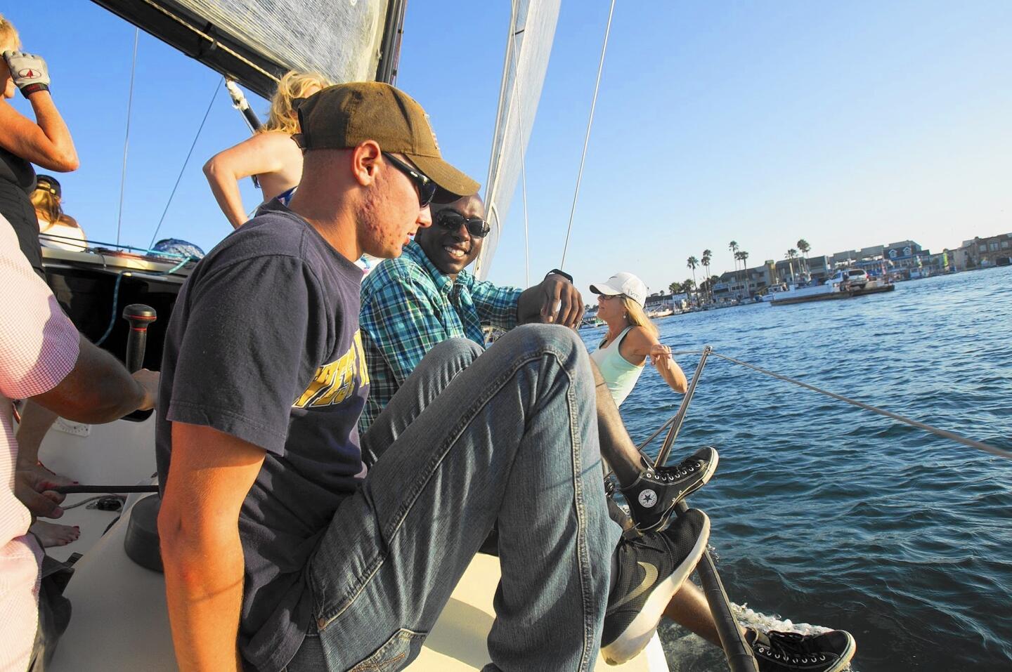 Pfc. Tyler Warner, left, and Pfc. Kris Tolbert of the 1st Battalion, 1st Marines from Camp Pendleton take an evening sail at Newport Harbor on Thursday on a 40-foot sailboat named Wild Thing with members of the Balboa Yacht Club.