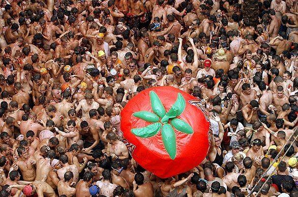 A crowd plays with a tomato balloon during La Tomatina festival. In an hour, 121 tons of tomatoes are demolished in the food fight.
