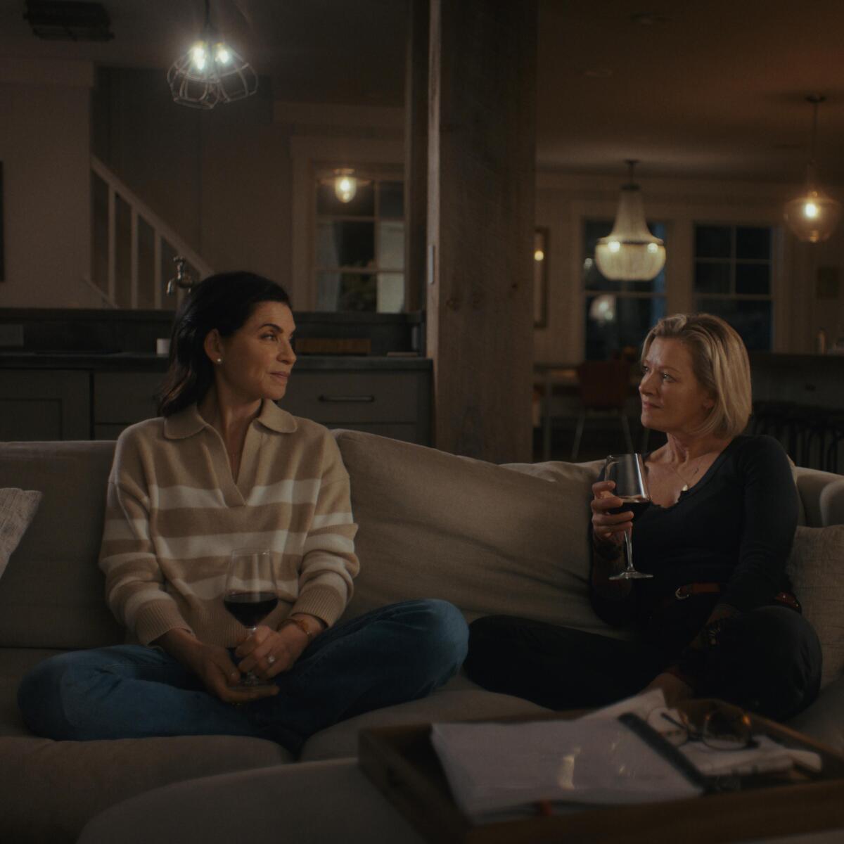 Julianna Margulies and Gretchen Mol sit on a couch in a living room talking