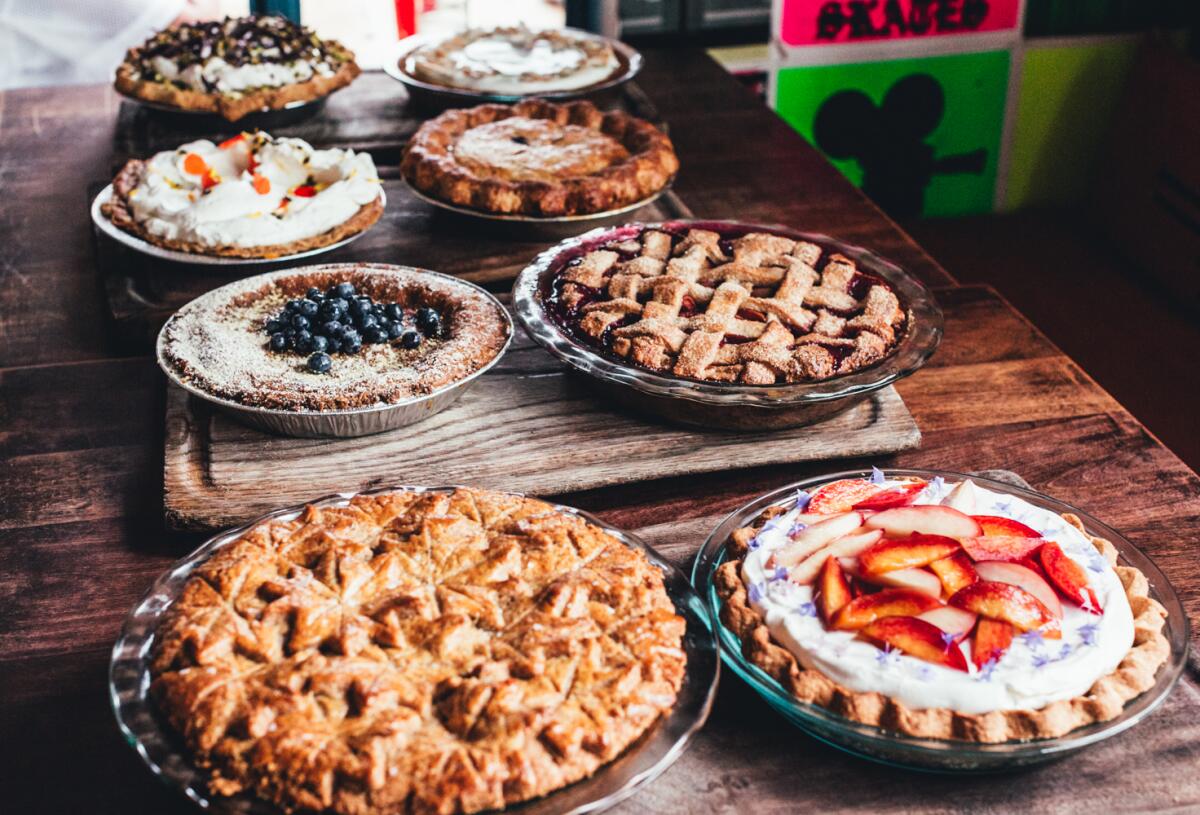 An assortment of pies on a dark wood table.