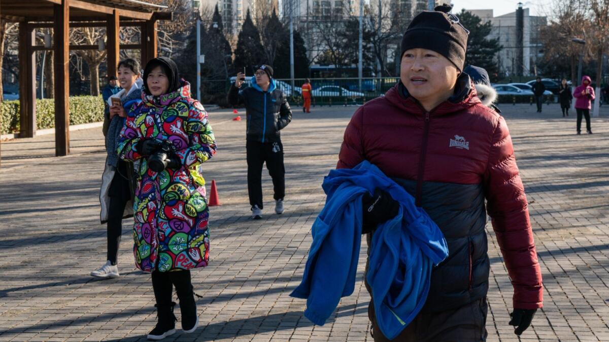 Parents watch their boys and hold jackets at the park.