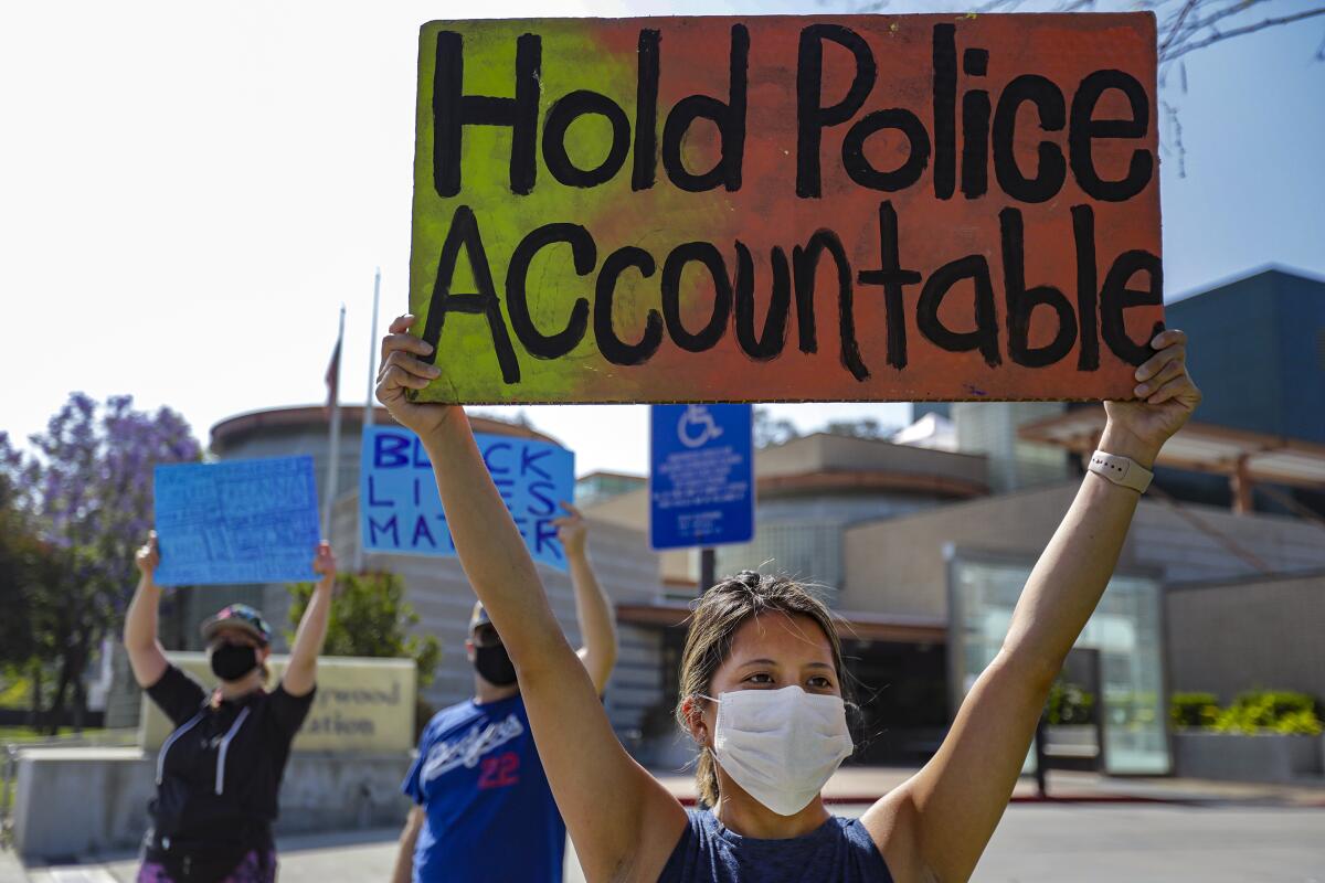 A woman holds a sign reading "Hold Police Accountable."