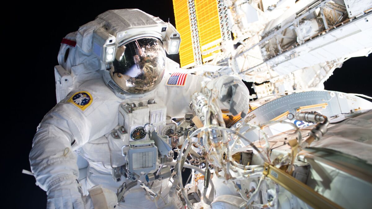 A NASA astronaut installs international docking adapters on the International Space Station.