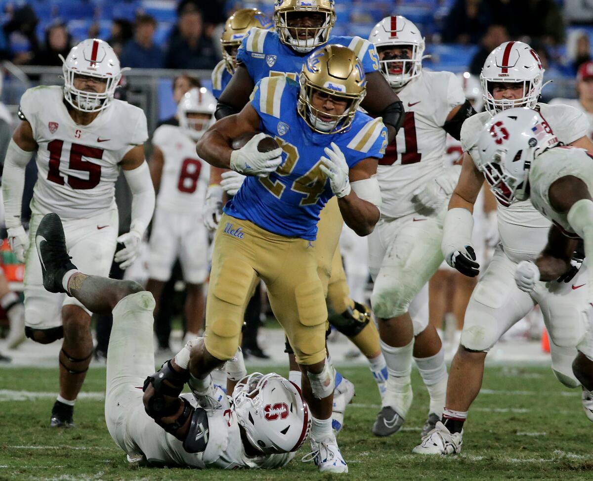 UCLA running back Zach Charbonnet runs over Stanford defenders on his way to scoring a touchdown.