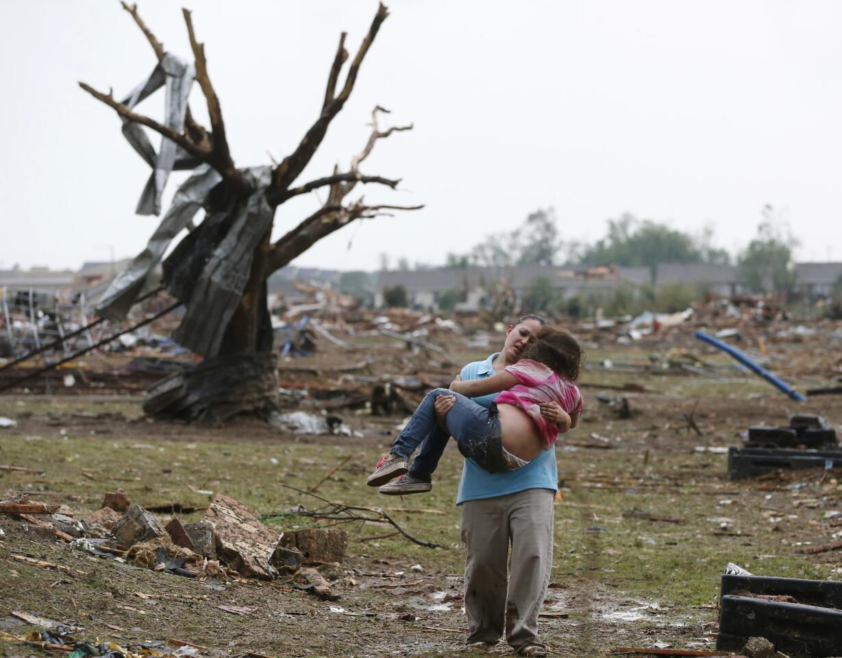 LaTisha Garcia carries her 8-year-old daughter, Jazmin Rodriguez, near Plaza Towers Elementary School after a massive tornado carved its way through Moore, Okla., leaving little of the school and neighborhood.