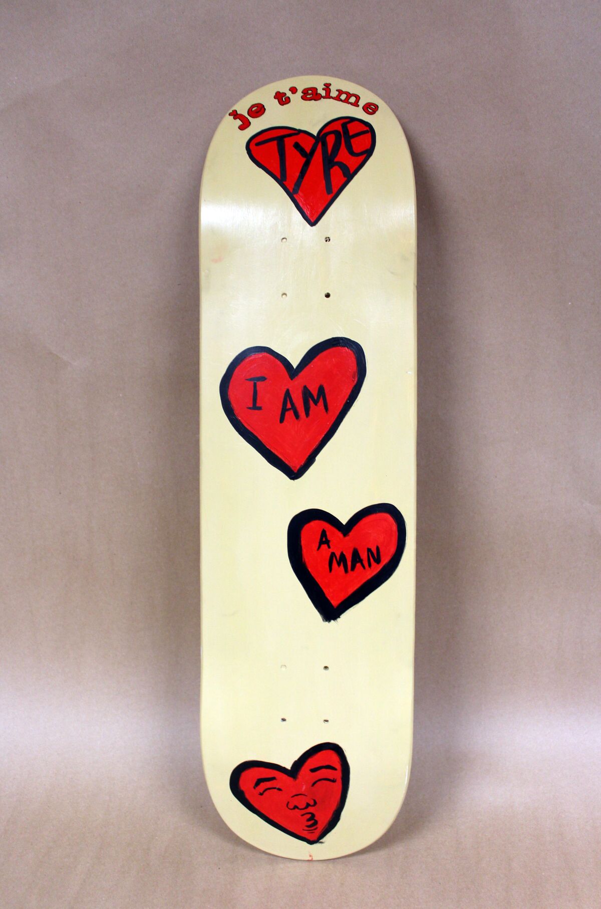 A skateboard with red hearts reads "je t'aime Tyre" and "I am a man."