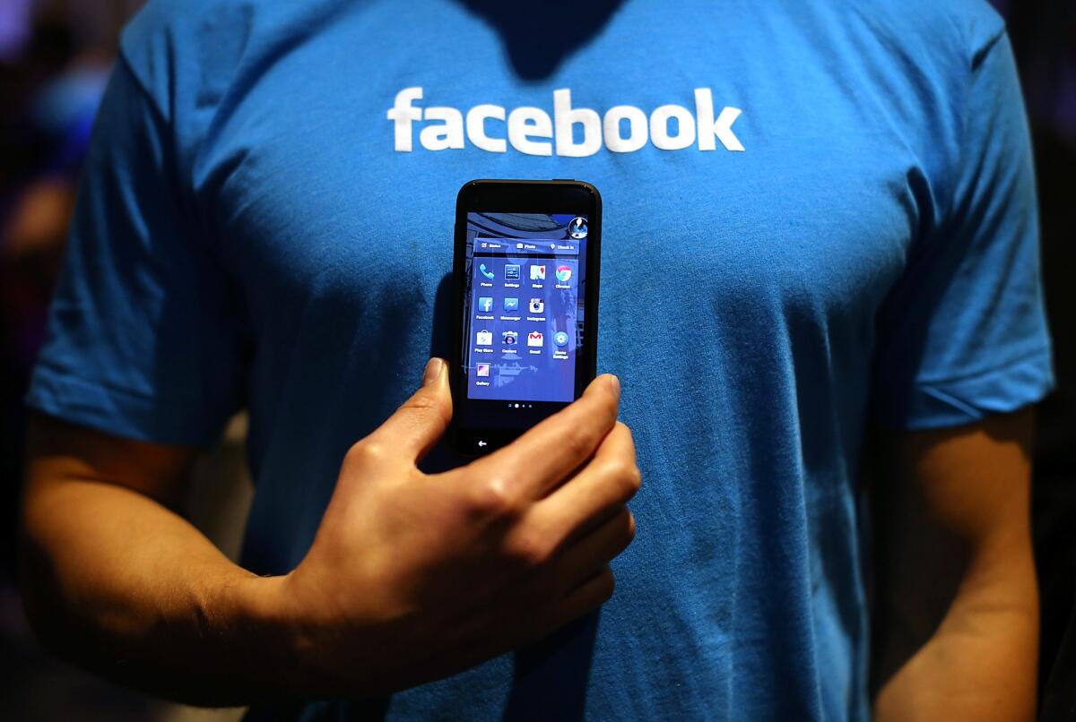 A Facebook employee holds a phone running the company's Home app in 2013. The app was among the selling points of the HTC First, a smartphone that Facebook helped develop.
