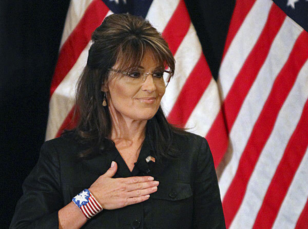 Former Alaska Gov. Sarah Palin covers her heart during the national anthem as she attends a public appearance at a Long Island Association (LIA) meeting and luncheon in Woodbury, N.Y.