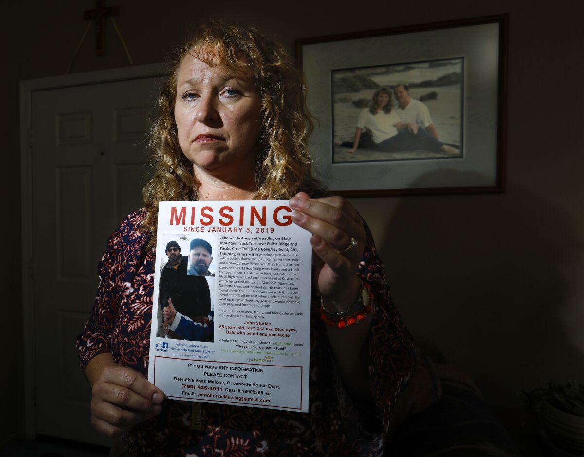 Theresa Sturkie  holds a missing poster at her home on May 21, 2019 in Oceanside, showing her husband of 21 years, John Sturkie, who has been missing since January 5