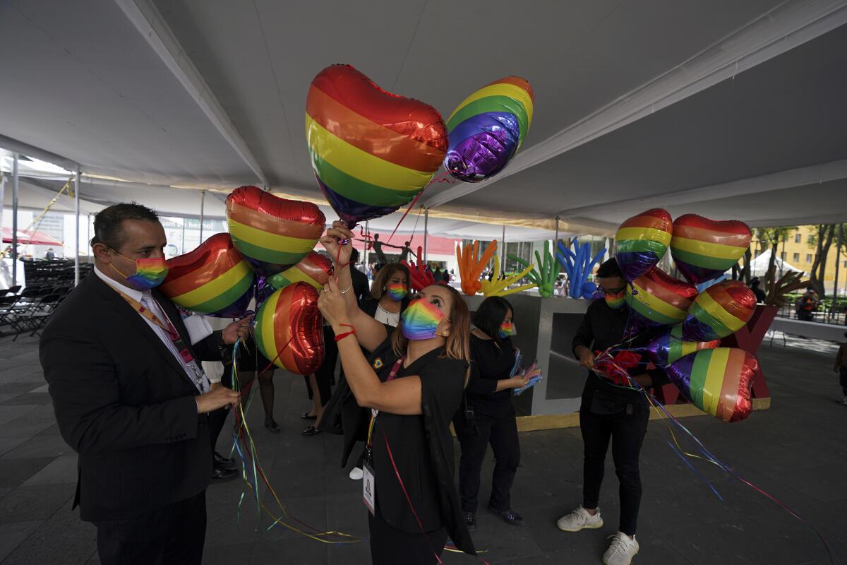 Office workers decorate with heart-shaped, rainbow-colored balloons for a same-sex mass wedding ceremony.