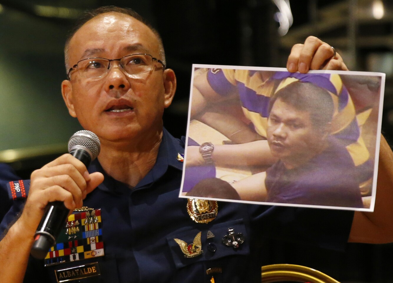 Police Gen. Oscar Albayalde holds an image of the Resorts World Manila attacker, whom he identified as Jessie Carlos at a news conference Sunday in Pasay.