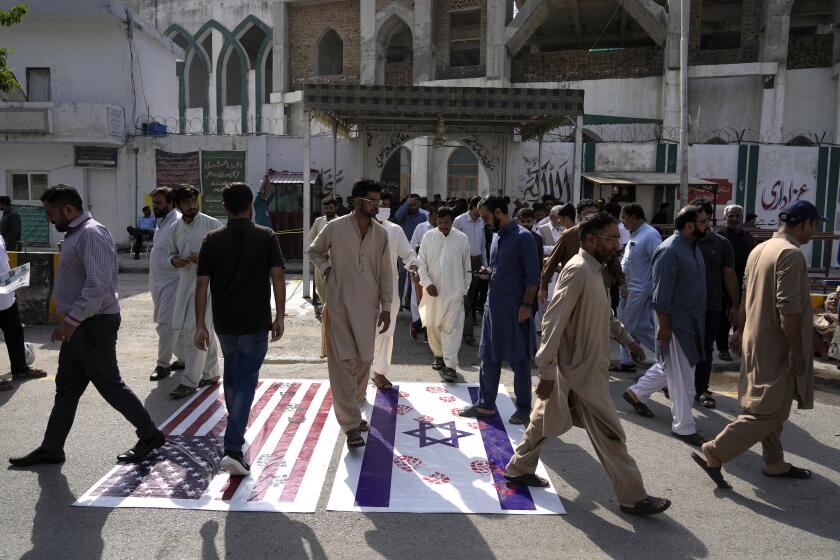 Musulmanes chiítas que salen de una mezquita después de las oraciones del viernes pisotean representaciones de las banderas estadounidense e israelí en repudio a los ataques aéreos israelíes a Gaza y solidaridad con los palestinos, en Islamabad, Pakistán, viernes 13 de octubre de 2023. (AP Foto/Anjum Naveed)