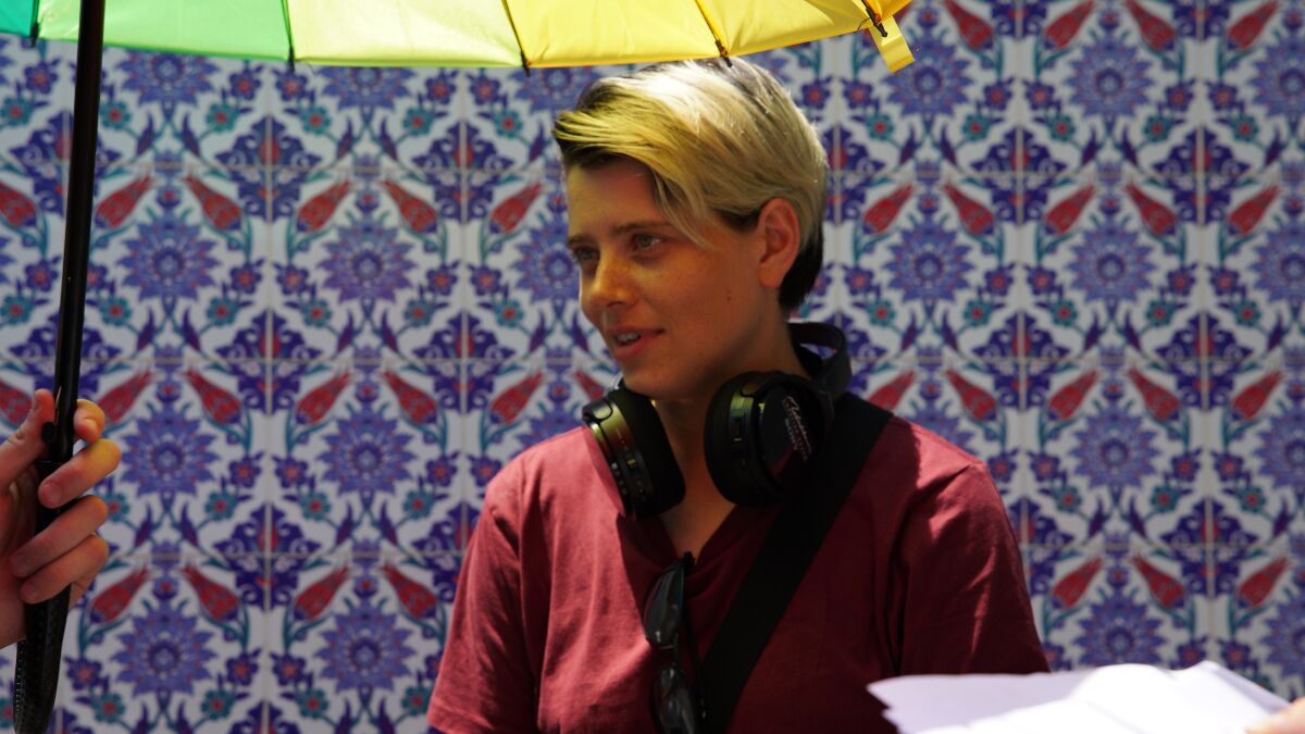 A woman underneath an umbrella with headphones around her neck 