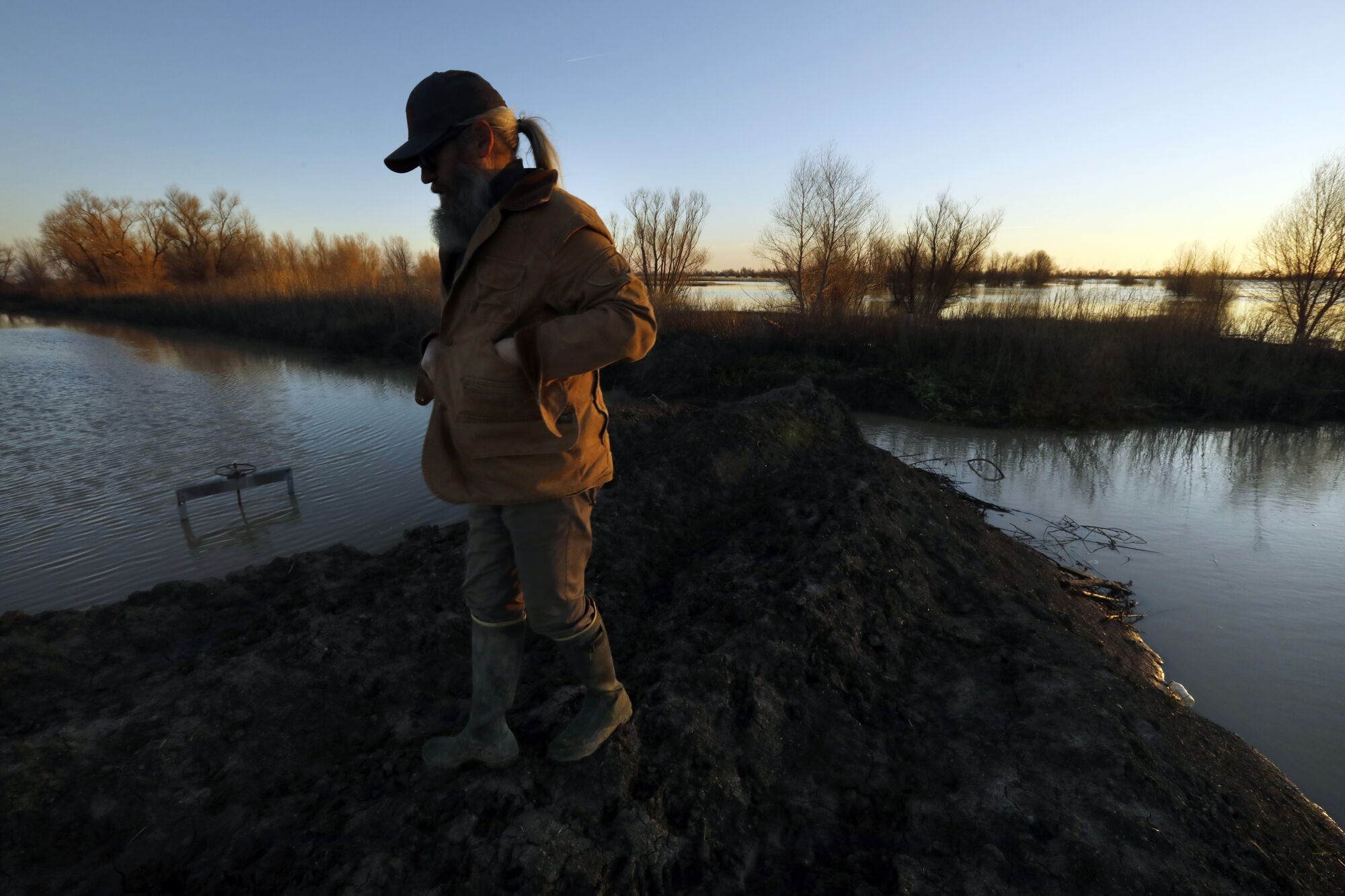 A man stands in the middle of flooded farmland.