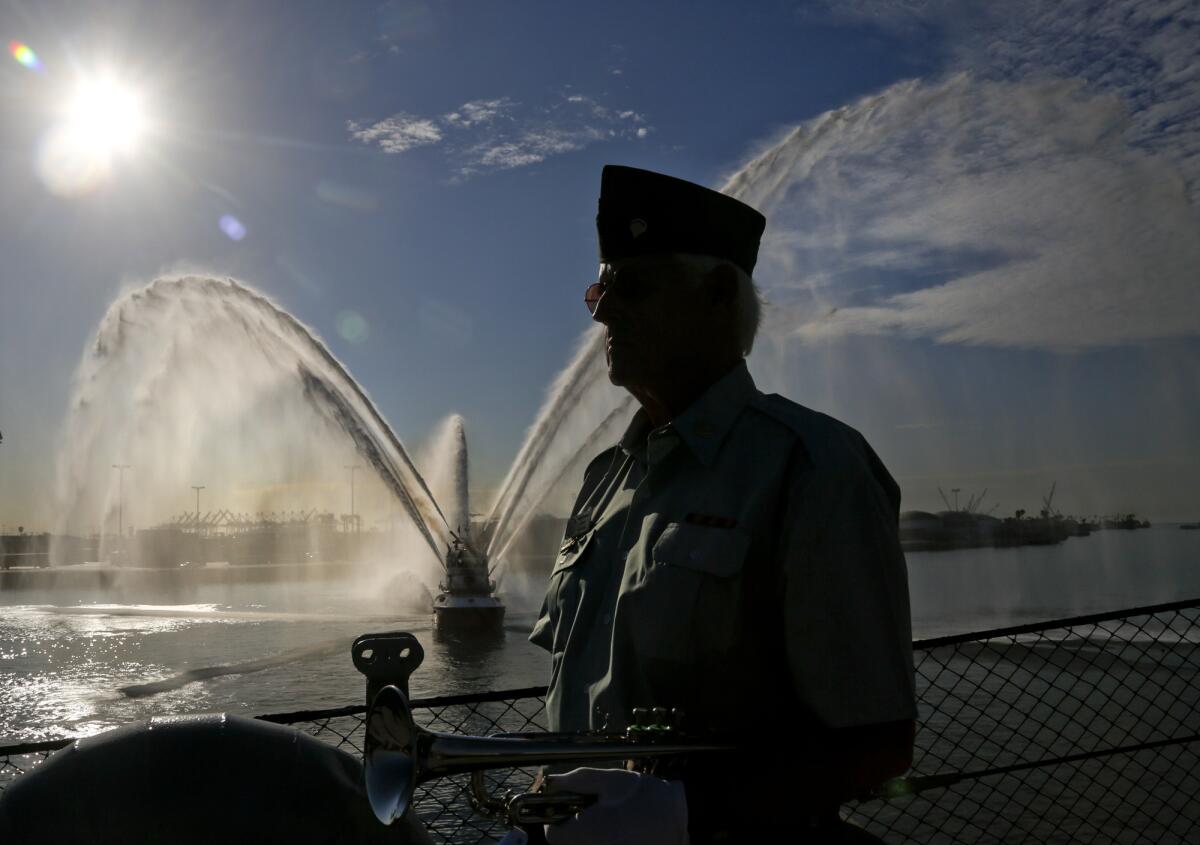 Bugler Terrence Stevens stands at attention after playing during a special 9/11 ceremony aboard the battleship USS Iowa in San Pedro while a fireboat shoots water into the air honoring the memory of those who lost their lives 14 years ago.