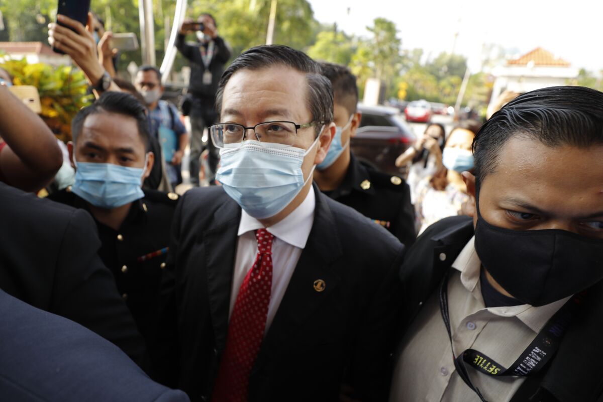 Former Finance Minister and Penang chief minister Lim Guan Eng, center, is escorted by Anti Corruption officers as he arrives at courthouse in Kuala Lumpur, Malaysia, Friday, Aug. 7, 2020. Lim was arrested last night to be charged with corruption in connection with the Penang undersea tunnel project, the Malaysian Anti-Corruption Commission (MACC). (AP Photo/Vincent Thian)