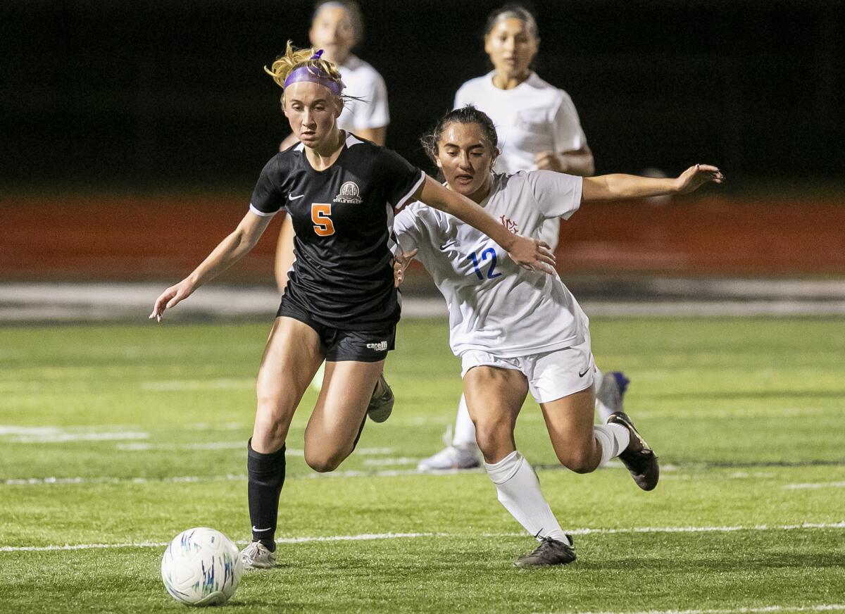 Huntington Beach's Sienna McAthy battles for a ball against Los Alamitos' Alina Perez during Monday's match.