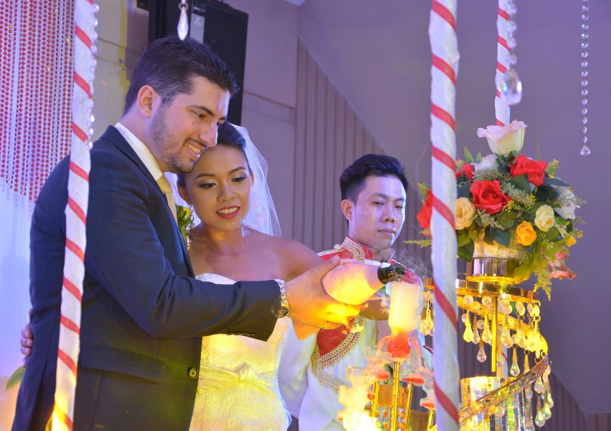 Alex Sarkisian and Nhu Le pour champagne into a champagne tower at their wedding reception in Da Nang, Vietnam. — Tran Van Lai